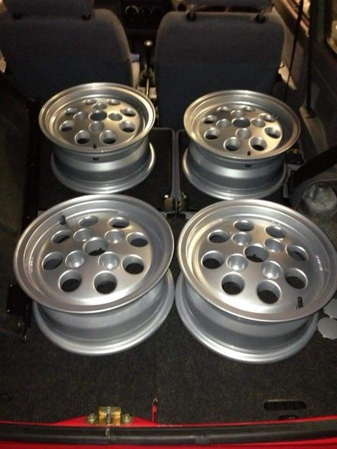 Four pepperpot alloy wheels laid out in the boot.